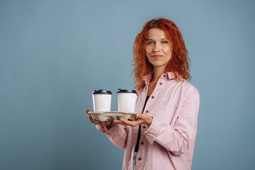 White cups of drinks, holding it. Woman is in the studio against background