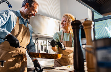 Couple enjoying a cooking class with a chef preparing meal in the kitchen.