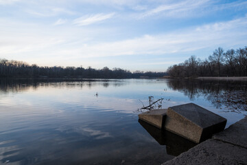 A peaceful and tranquil lakeside scene captured beautifully at dusk, showcasing calm waters, gentle...