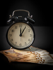 Alarm clock and money on black background. Time is money concept