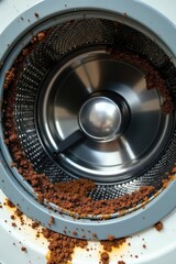 Close-up view of a washing machine drum heavily soiled with coffee grounds residue, requiring thorough cleaning.