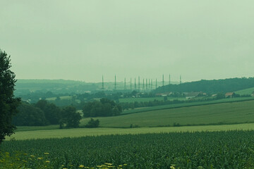 Electric towers rise above rural fields in mist