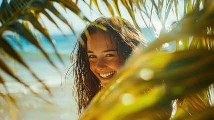 Joyful woman smiling through green palm leaves at the beach. A moment of happiness and peace captured in sunny nature.