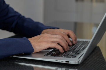 Professional Hands Typing on Laptop Keyboard in Modern Workspace