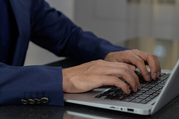 Person in Suit Using Laptop with Focused Hands on Keyboard