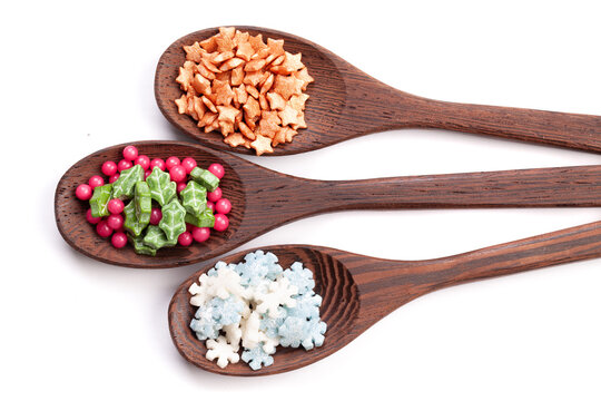 Wooden spoons with cake confectionery sprinkles on white