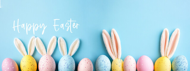 happy easter holiday celebration banner panorama long with text - easter eggs with easter bunny ears, isolated on pastel blue background