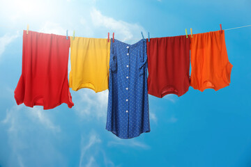 Different clothes drying on washing line against blue sky