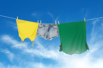 Different clothes drying on washing line against blue sky