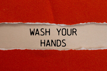 Wash your hands message written on ripped torn red paper with beige background. Conceptual wash your hands symbol. Copy space.