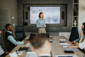 A diverse group of business people engaged in a meeting with a presentation displayed on a screen....