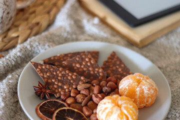 Books, e-reader, tea, orange juice, fruit, snacks, yarn, blanket and lit candles on the table. Autumn or winter hygge at home. Selective focus.