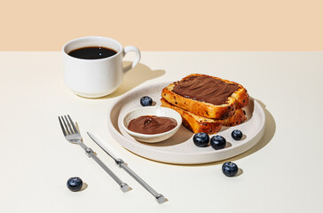 Toasted bread with chocolate cream on a plate with blueberry on a light  background