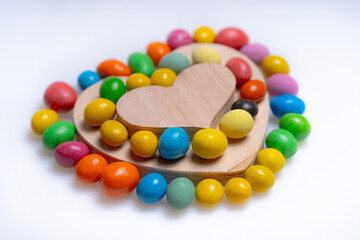 Wooden candy heart art. A decorative heart shape surrounded by colorful candy eggs on a white background, perfect for celebrations.