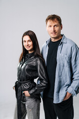 Couple confidently poses casually. A couple stands side by side, smiling, wearing stylish casual clothes in a neutral studio setting.
