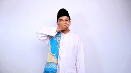 handsome asian muslim youth gesture covering mouth with his hand on isolated white background