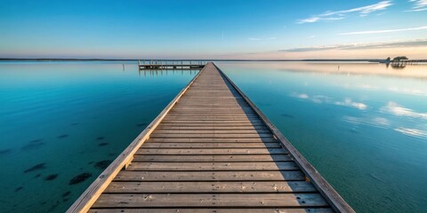 Fototapeta premium Serene Wooden Dock Extending into Calm, Teal Waters at Sunrise