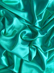 Fototapeta premium Elegant smooth blue satin, silk fabric drapes. Luxurious cloth textile with liquid wave. Abstract turquoise background or template. Fabric shiny glitter texture. Luxurious light blue background. 