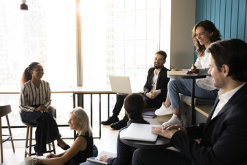 Six professionals engaged in lively and informal meeting in modern office, having friendly...