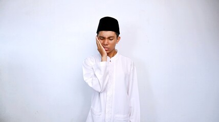 young asian muslim man expression of pain toothache gesture hand holding cheek with isolated white background