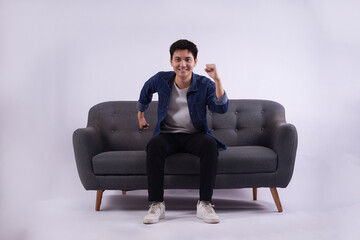 Full body image of young Asian man posing on sofa on white background