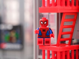 Naklejka premium Tambov, Russian Federation - January 06, 2025 Lego Spiderman minifigure sitting on the fire escape stairs of the building