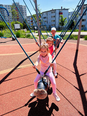 Children playing together on a swing in an outdoor playground