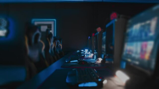 Modern cyber computer club for videogames and E-sport tournament. Gaming armchairs, mouses and keyboards with RGB lighting animation, mats. LAN cafe. No one, nobody. Handheld shot. Tilt-shift lens