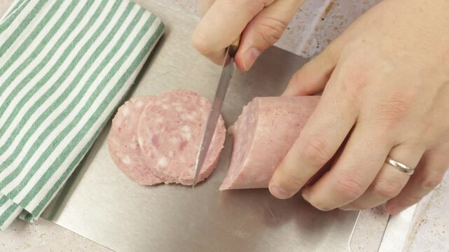 gros plan sur une personne coupant un saucisson &agrave; l'ail