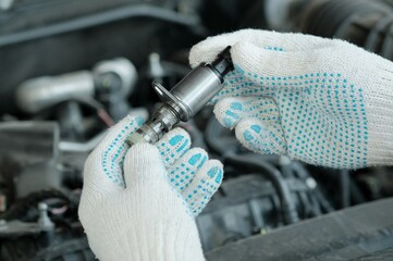 The VVT-i system (Variable Valve Timing intelligent — valve timing changes).A new VVT-I valve is in the hands of an auto mechanic. A specialist checks the serviceability of a new spare part.