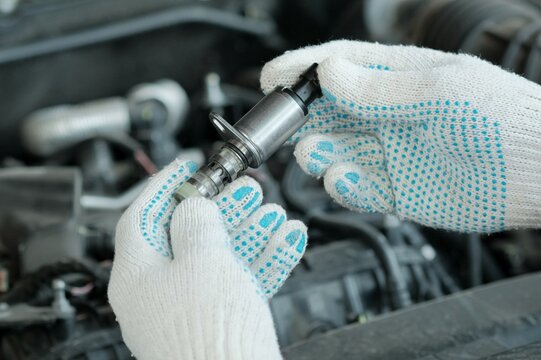 The VVT-i system (Variable Valve Timing intelligent &mdash; valve timing changes).A new VVT-I valve is in the hands of an auto mechanic. A specialist checks the serviceability of a new spare part.
