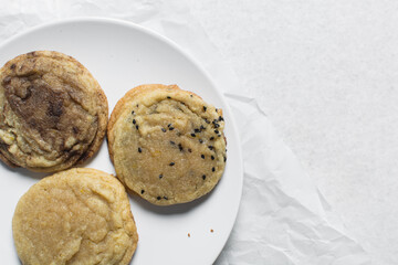 Overhead view of different types of sugar cookies, vanilla cookies, cinnamon cookie, black sesame sugar cookie on parchment paper