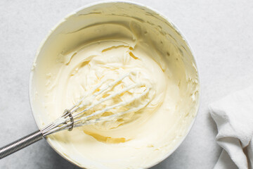 Top view of cream buttercream in a white mixing bowl, silky smooth american buttercream in a ceramic bowl, overhead view of smooth buttercream