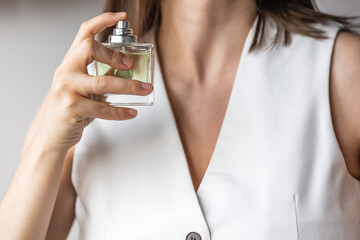 woman holds bottle of transparent green perfume. There is no face. Concept: self-care. Hobbies:...