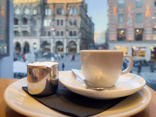 White cup of coffee and milk on plate with views to Marienplatz in Munich, Germany. European tourism, cafe tour break concepts