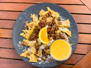 German strudel stuffed with walnuts, raisins, powdered sugar, orange slice on top and cream liquor glass. Scrambled pancake, classic sweet pie dessert concept
