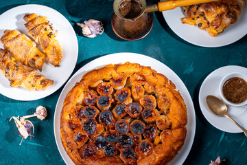 Traditional homemade banana caramel pie. French Tarte Tatin on a white plate with Turkish coffee on a green, emerald background.