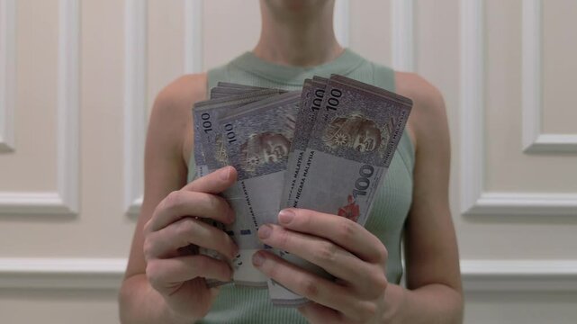 Woman counting the Malaysian ringgit - the currency of Malaysia, close-up