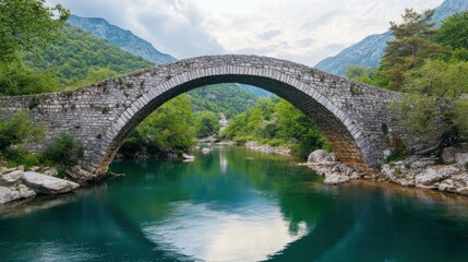 Fototapeta premium Ancient Stone Arch Bridge Over Serene Green River Valley