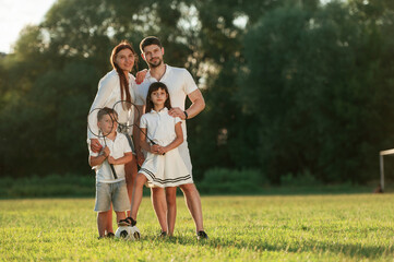 Happy family is standing together on the field