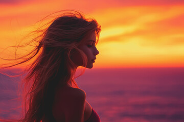 A woman with long hair standing on a sandy beach looking at the ocean waves on a sunny day with a clear blue sky in the background