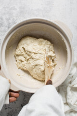 Overhead view of bread dough being mixed in a donabe, top view of homemade bread dough being mixed on granite countertop, process of making artisan bread