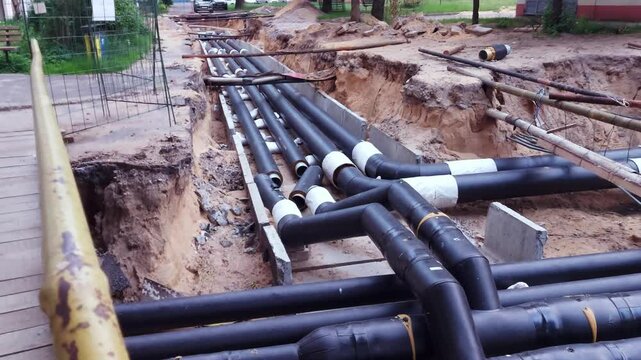 Replacing old underground hot water heating pipes with new ones. Excavation of the earth and repair of the heating main, industry