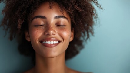 serene woman with radiant skin smiles gently, showcasing her natural beauty and joy. Her curly hair frames her face, enhancing her cheerful expression