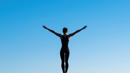 Obraz premium Silhouette of a Gymnast Performing an Aerial Routine Against a Clear Blue Sky