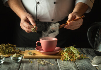 An experienced herbalist brews a healthy tea from medicinal dry herbs. A hand holds a spoon with...