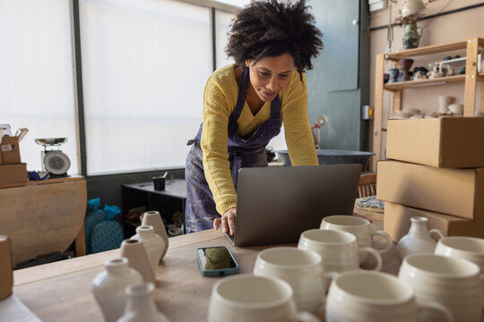 Woman Working on Laptop in Pottery Studio Space