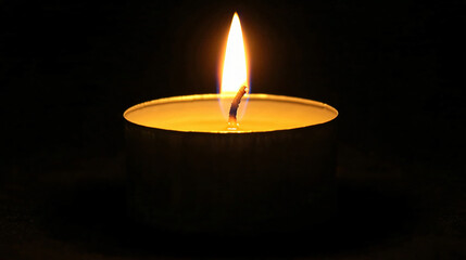 A single candle burning in the darkness, its soft glow illuminating the surrounding shadows, symbolizing hope and resilience.