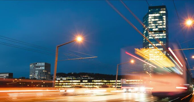 27-01-2025 Zurich, Switzerland. Time lapse of cars and public transport on a busy Hardbrucke bridge at night. Bridge side view, famous Prim Tower skyscraper building in the background