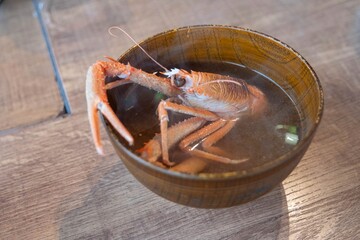 A red crab sitting in a steaming bowl of miso soup with thick broth at a restaurant in Japan. 